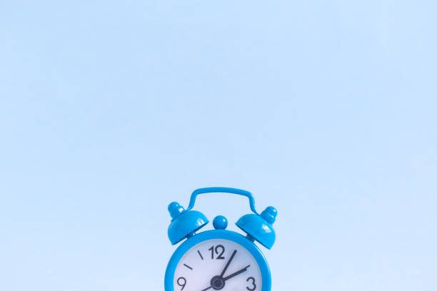 istock Flat lay of small alarm clock on blue background 936213282