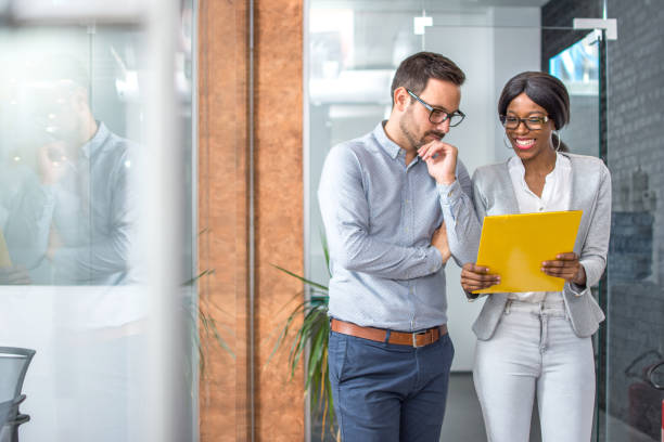 istock Concentrated man and woman examining business plan while standing in office 936235614