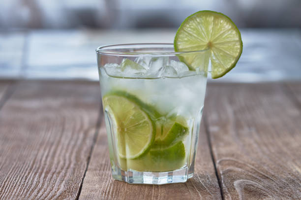 Caipirinha with ice and lime on a wooden table. Summer soft drink.