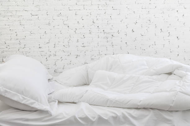 istock White bedding sheets and pillow in white room background. Messy bed concept in moring time. 936240698