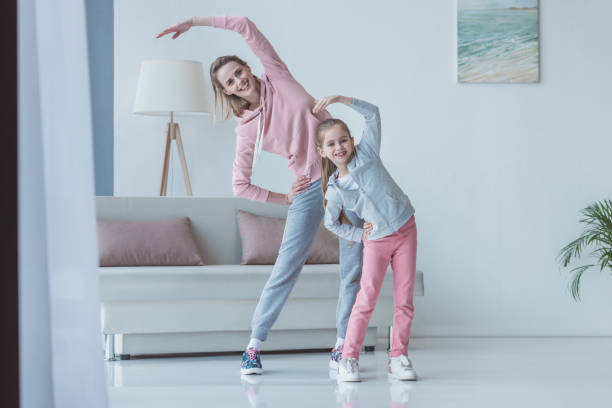 istock fit mother and daughter doing side bends at home 936252062