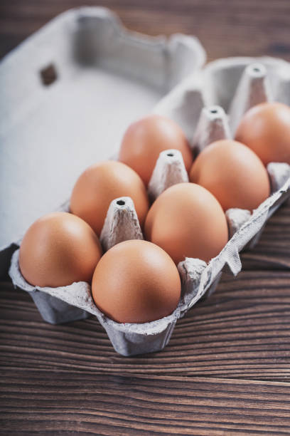istock Close-up of raw chicken eggs in a box. Eggs on an old wooden table 936268030