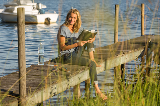 beautiful woman reading book near lake