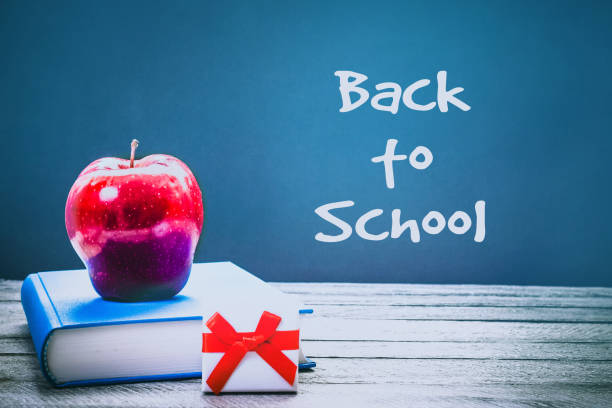 istock Back to School and Education concept. book, red apple and gift box on chalkboard background. school border with copy space 936272902