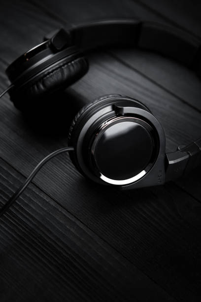 istock Black headphones on black wooden dark background. 936276810
