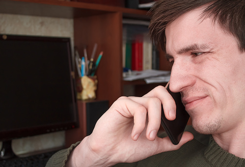 young guy talking on a black smartphone with a smile