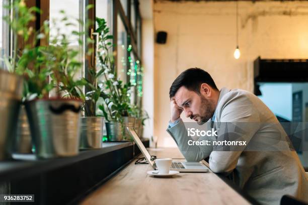 Hombre Preocupado Mirando La Pantalla Del Ordenador Portátil Mientras Está Sentado En El Café Moderno Foto de stock y más banco de imágenes de Confusión