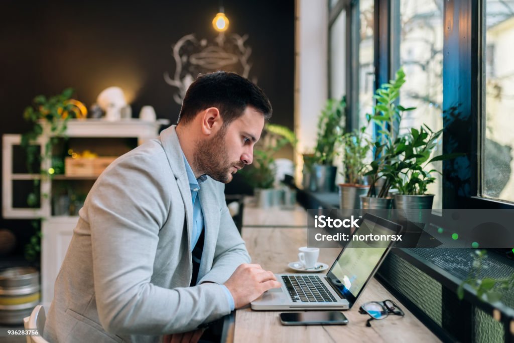 Serious businessman working on a laptop at the cafe. Adult Stock Photo