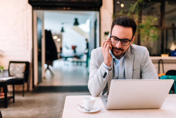 istock Working with pleasure. Young man talking on the mobile phone and looking at his laptop while sitting at the cafe. 936283788