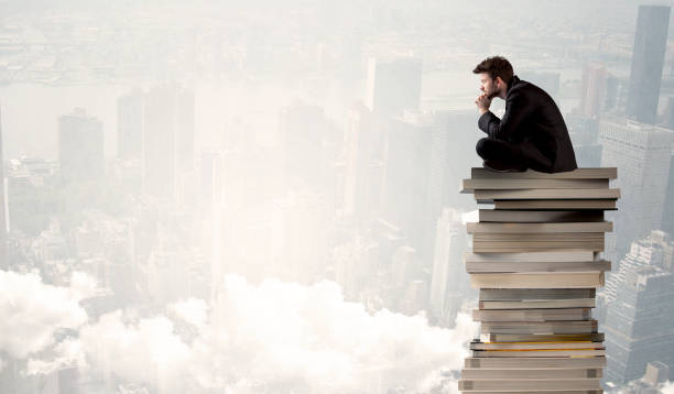 istock Student in city sitting on stack of books 936285206