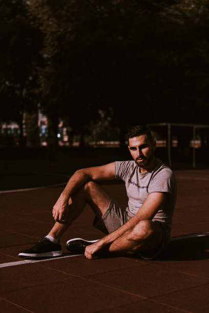 istock Young handsome man sitting and resting after hard training at stadium. 936285864