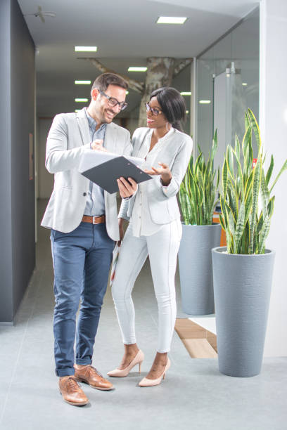 istock Two business people working together with documents while having informal meeting in office hallway. 936286262