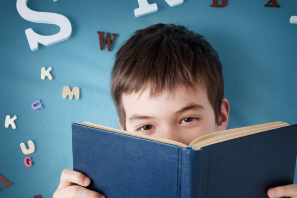 istock seven years old child lying with book and letters 936286902