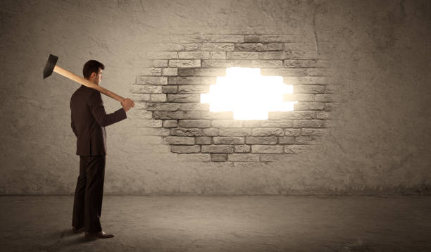 istock Business man hitting brick wall with hammer and opening a hole 936288878