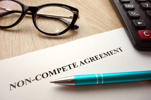 Non-compete agreement document for filling and signing on desk, 
business competition concept