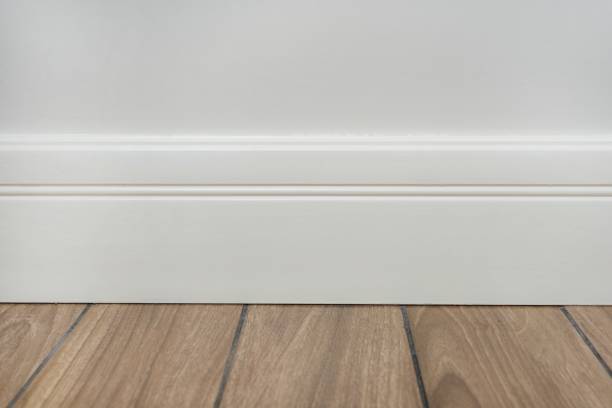 Light matte wall, white baseboard and tiles immitating hardwood flooring Interior concept. Light matte wall, white baseboard and tiles immitating hardwood flooring moulding trim photos stock pictures, royalty-free photos & images