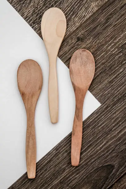 Wooden spoons on white paper and brown wooden background
