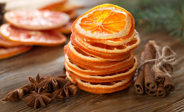 Christmas tree from dry oranges, cinnamon and anise stars on wooden rustic table and fir tree in background