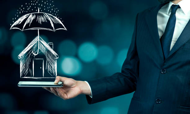 istock Businessman hand tablet with umbrella over house 936305220