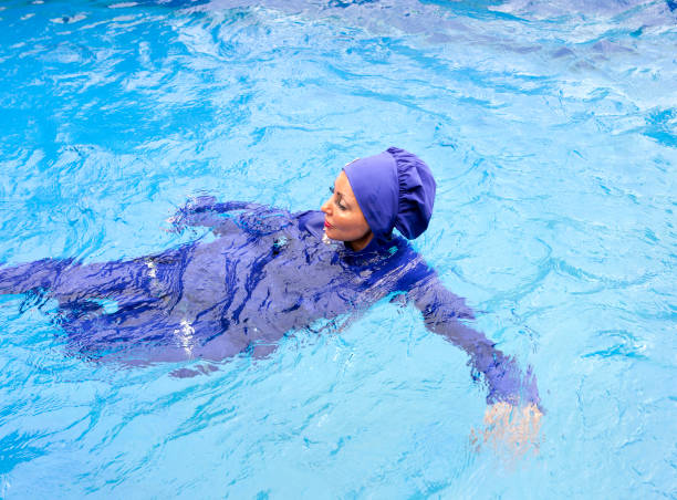有吸引力的婦女在穆斯林泳裝 burkini 游泳在水池 - 回教泳裝 圖片 個照片及圖片檔