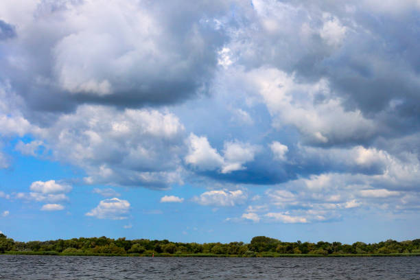 istock Thunderclouds over the Danube river in the spring. The strong wind and clouds pass on river. Dark dramatic rain clouds over countryside landscape 936311198
