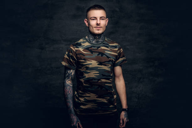 a man with tattoos on his neck, face and arms, dressed in a camouflage t shirt. - costume mustache child disguise imagens e fotografias de stock