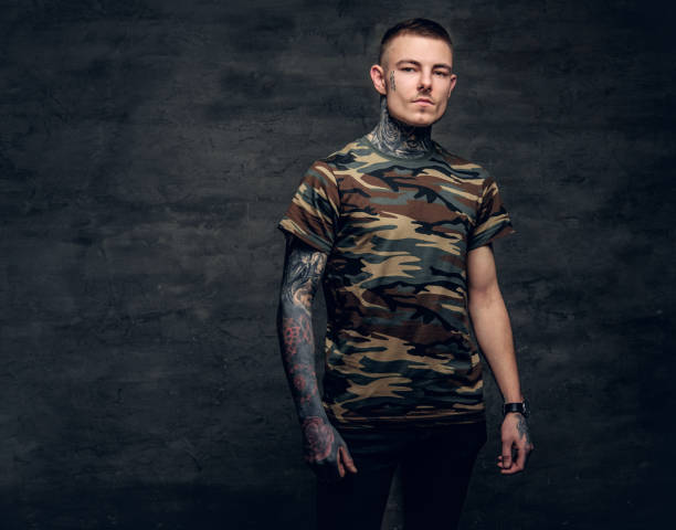 a man with tattoos on his neck, face and arms, dressed in a camouflage t shirt. - costume mustache child disguise imagens e fotografias de stock