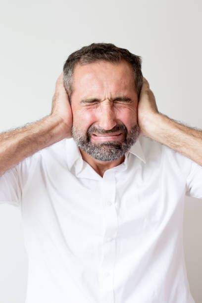 istock handsome man covering up his ears in pain 936313126