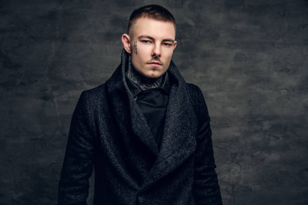 istock A man with tattoo on his face, dressed in a jacket over grey background. 936313762