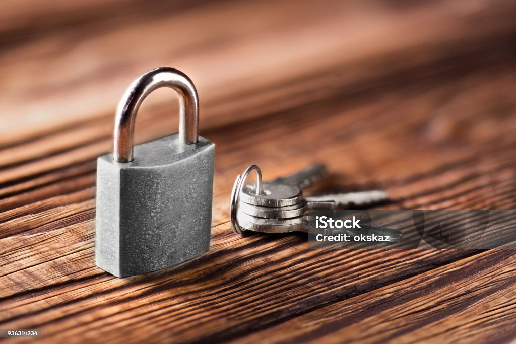 metal padlock with silvered keys on old wooden background. Estate and security concept with symbol of protection. Accessibility Stock Photo