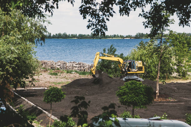 Yellow excavator digs soil on river bank