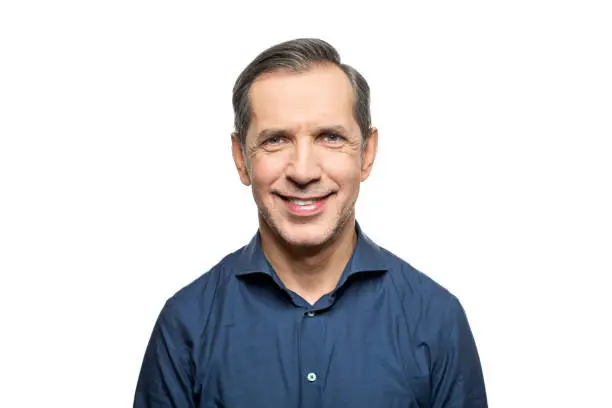 Portrait of happy mature man against white background. Male is smiling. He is wearing blue formal shirt.