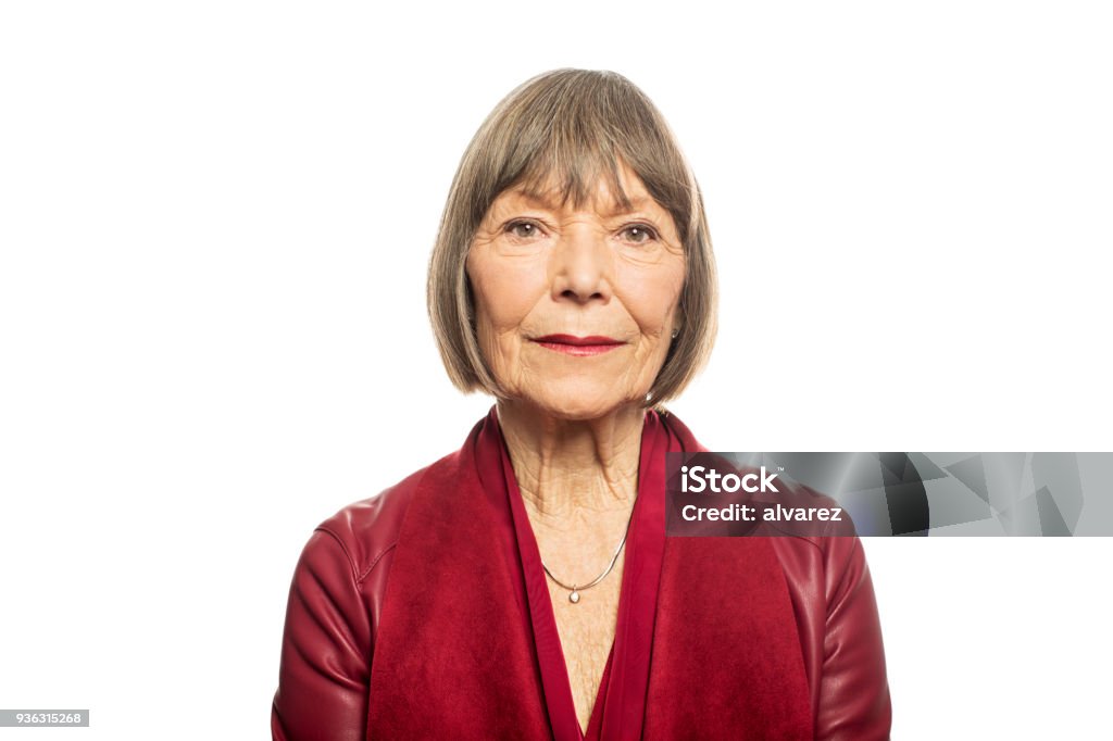 Portrait of senior woman against white background Portrait of senior woman against white background. Serious female is having short brown hair. She is wearing maroon casuals. Senior Women Stock Photo