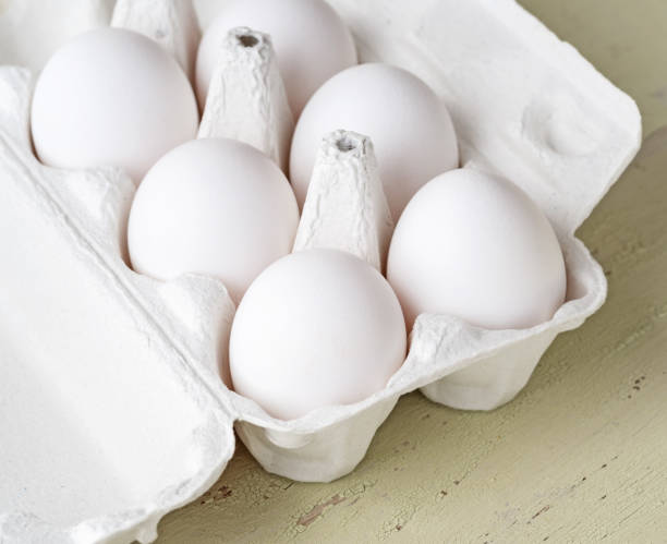 istock Carton egg stand with eggs on a light wooden background 936316262