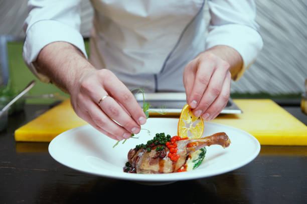 istock Chef is decorating a dish with dried orange and pea sprout, toned 936316520
