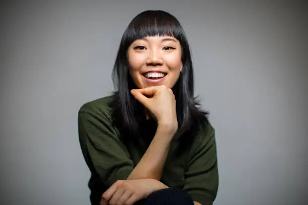 Photo of Cheerful woman sitting against gray background