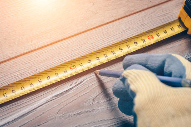 istock A worker with a construction measuring tape makes measurements on a wooden floor 936318780
