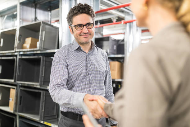 istock Businessman shaking hands with colleague in warehouse 936321178