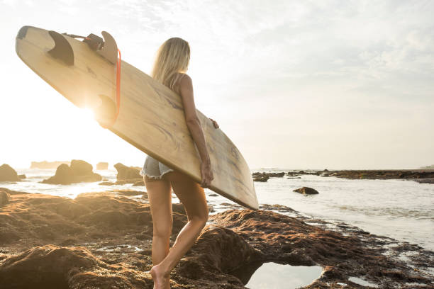 istock Pretty woman with surf board going to sea at sunset 936331394