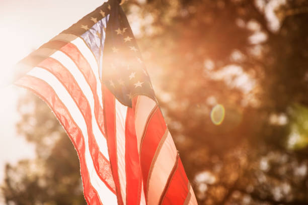 USA flag background for Memorial Day, July 4th. American flag blowing in the breeze on a spring or summer day with lens flare.  No people in this patriotic holiday or election image. us memorial day photos stock pictures, royalty-free photos & images