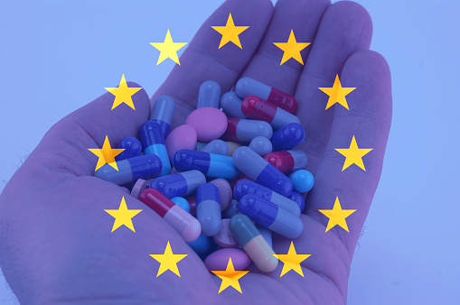 Hand holding multicolored pills, European union flag background