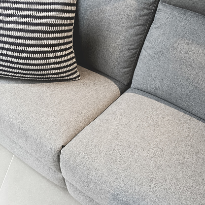 Striped cushion decorating a gray textile sofa. Comfortable furniture.