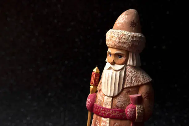 The grandfather of the cold, the Santa Claus of Russia, in figurine carved in wood and painted by hand, on a black background.