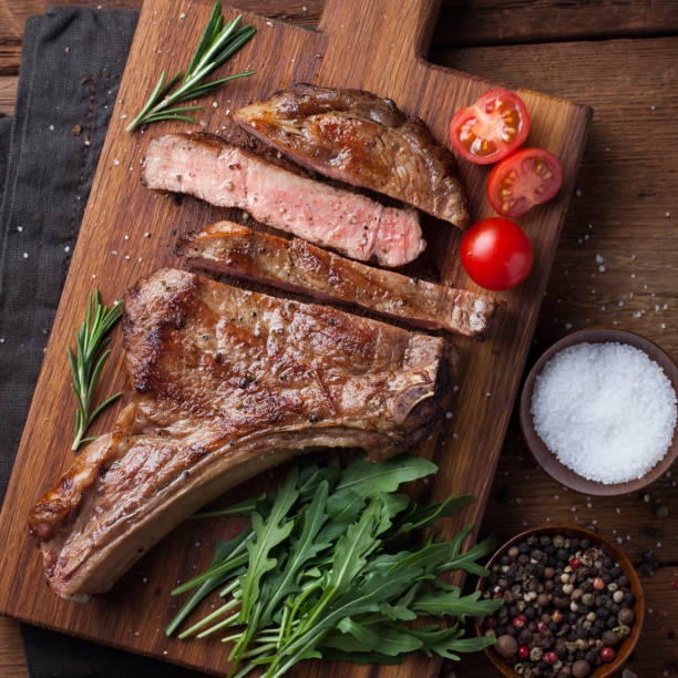 istock Grilled cowboy beef steak, herbs and spices on a rustic wooden background. Top view 936338580