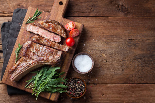 istock Grilled cowboy beef steak, herbs and spices on a rustic wooden background. Top view with copy space for your text 936338708