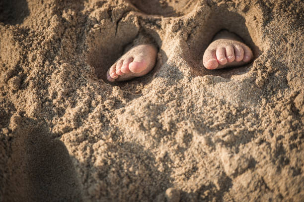 istock Children's feet are buried in sand 936339754