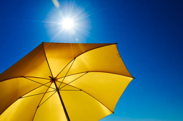 ombrello giallo con sole splendente e cielo blu - parasol umbrella sun beach foto e immagini stock