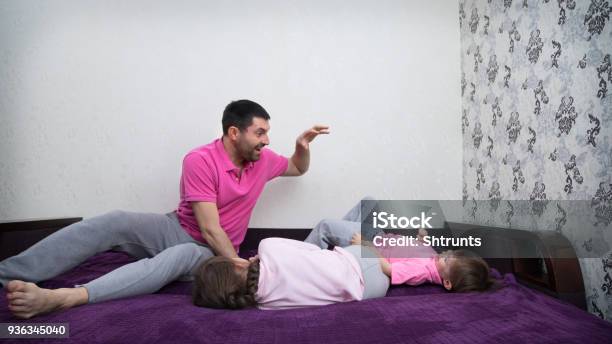 Father And His Two Kids Are Playing On Bed Stock Photo - Download Image Now - Black Color, Men, Simple Living