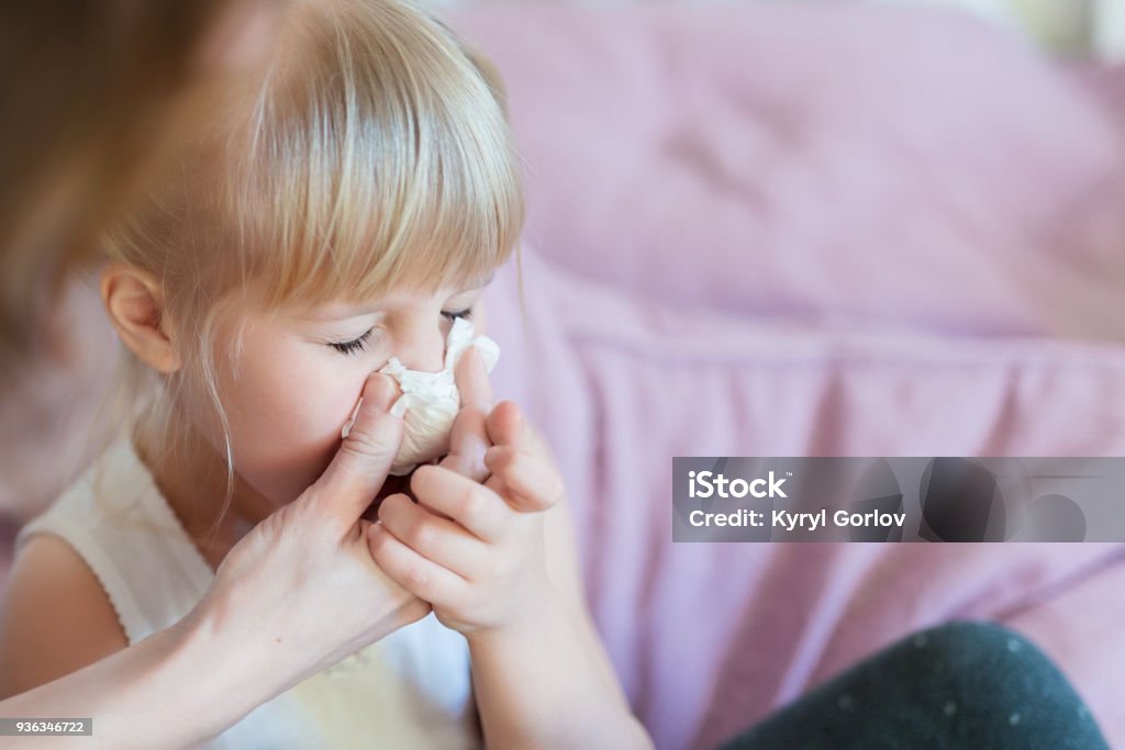 Child with runny nose. Mother helping to blow kid's nose with paper tissue. Seasonal sickness Child with runny nose. Mother helping to blow kid's nose with paper tissue. Seasonal sickness. Child Stock Photo