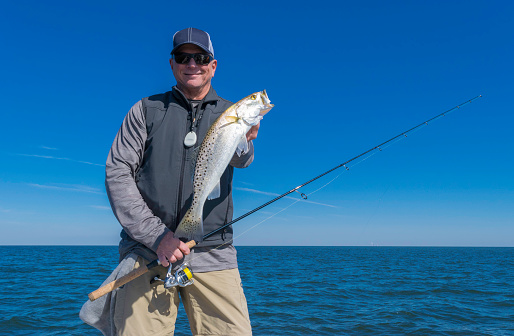 A fisherman holding a large speckled sea trout.